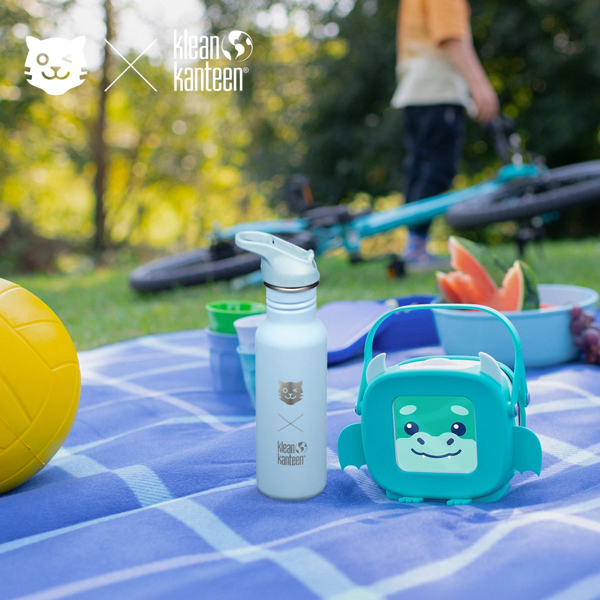 tigerbox MINI und Klean Kanteen Trinkflasche stehen nebeneinander auf einer Picknickdecke.